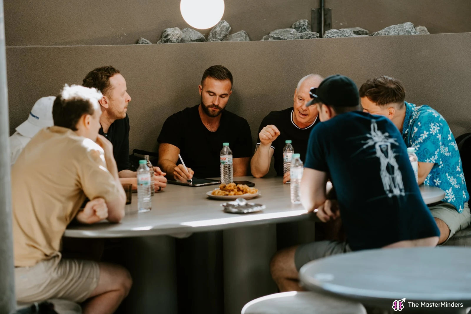 A small group discussing ideas and taking notes around a table at a previous Masterminders event.